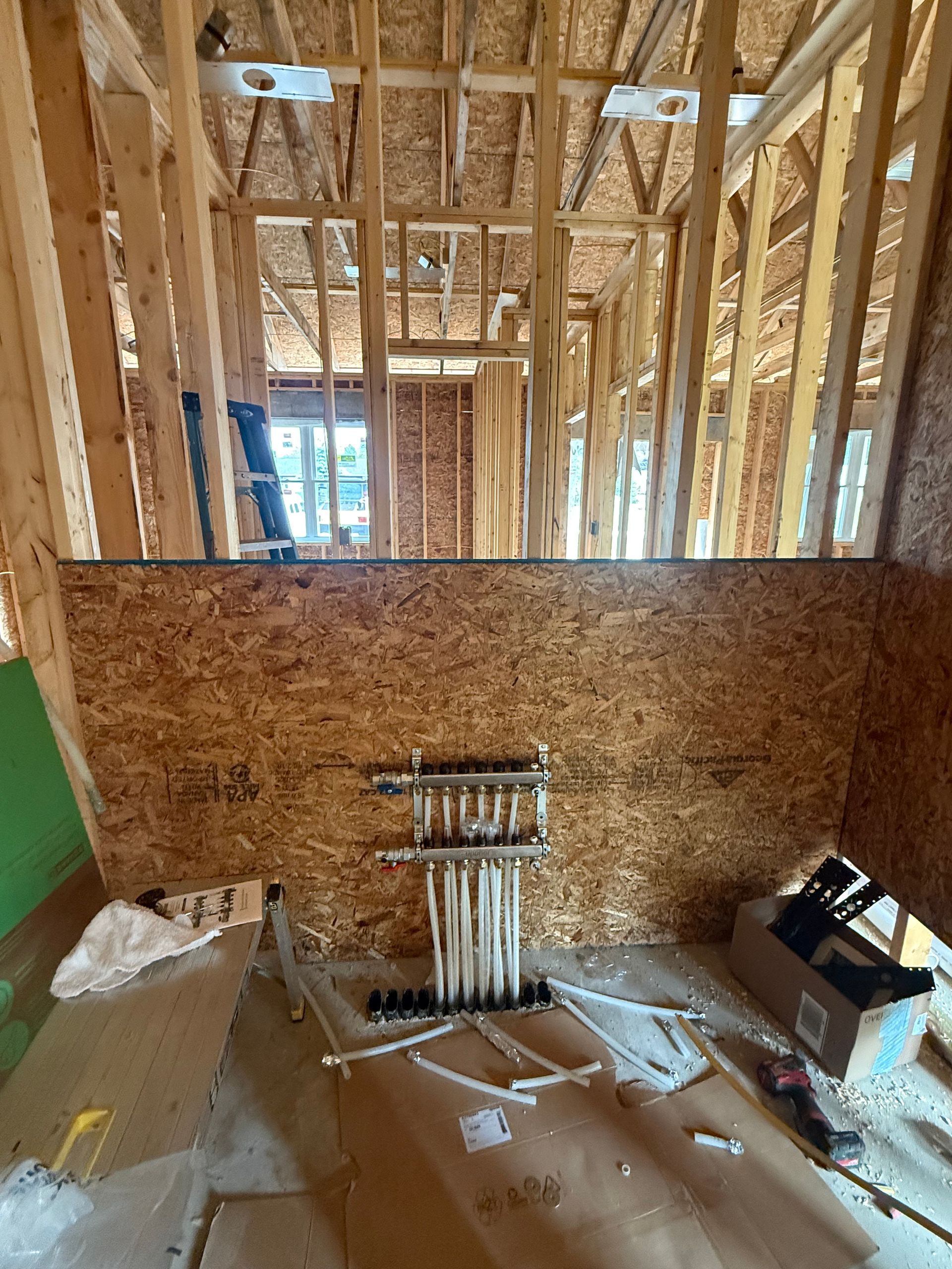 Interior of a house under construction, with exposed wood framing and electrical wiring on an unfinished wall.