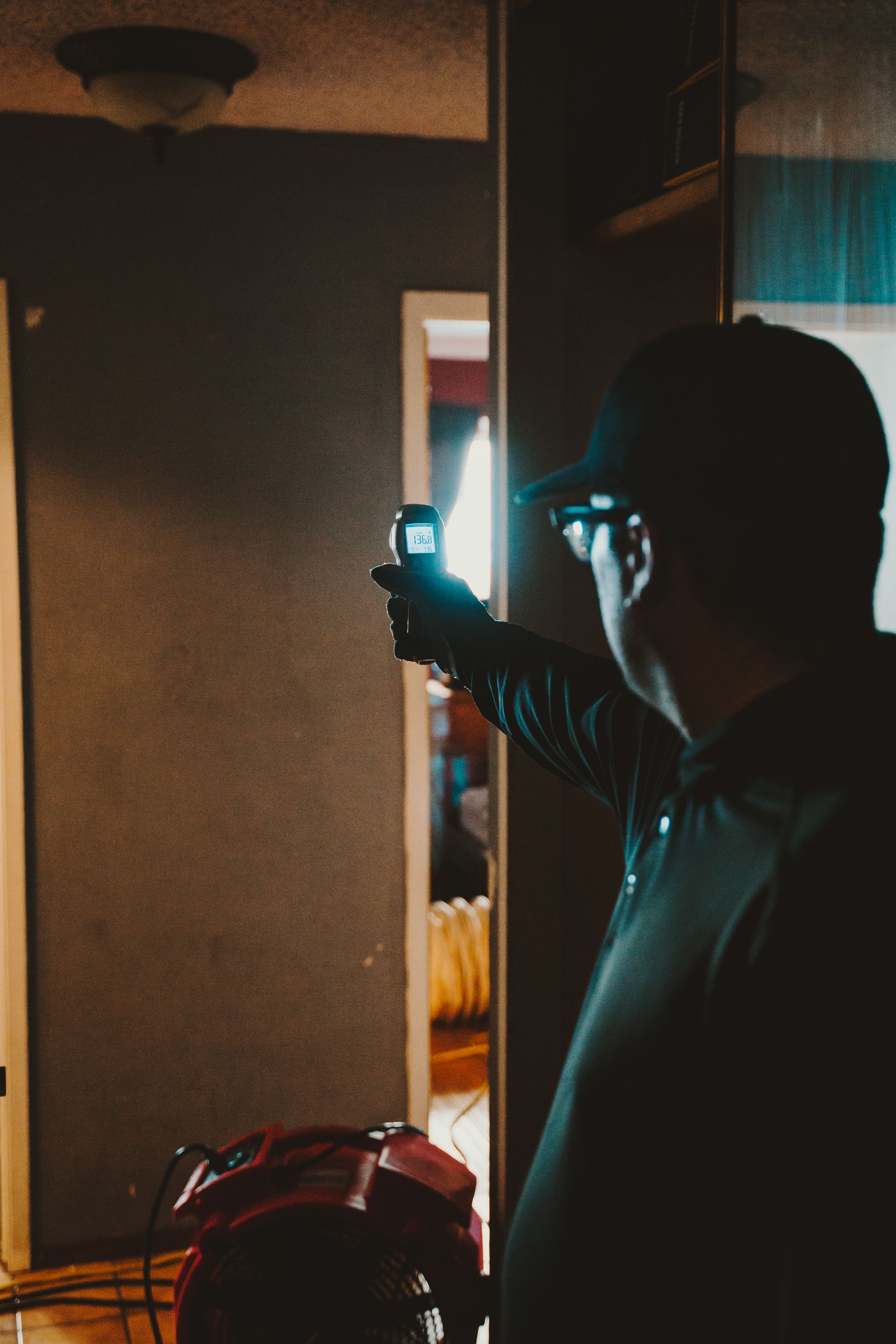 A man in a black hat is holding a flashlight in a dark room
