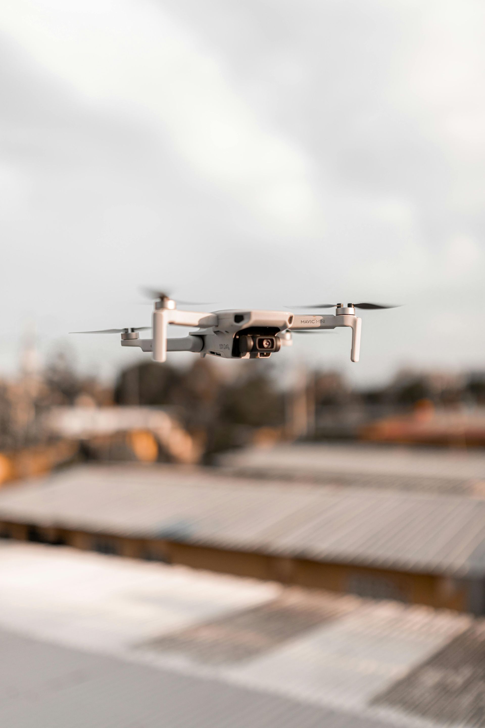 A small white drone is flying over a building.