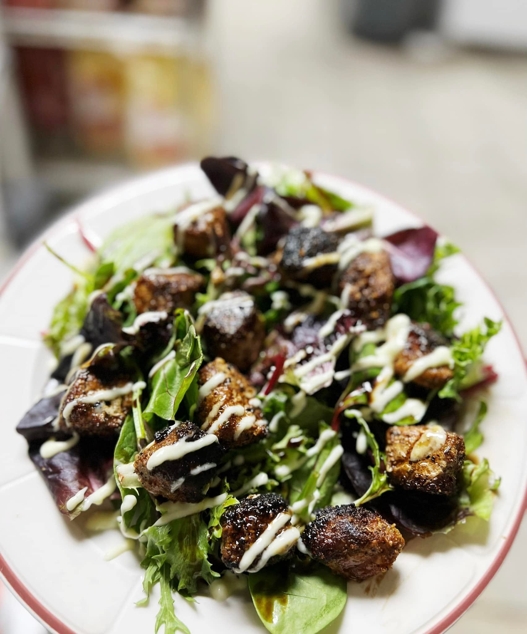 a white plate topped with a salad of meat and vegetables