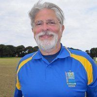 A man with a beard and glasses is wearing a blue and yellow shirt.