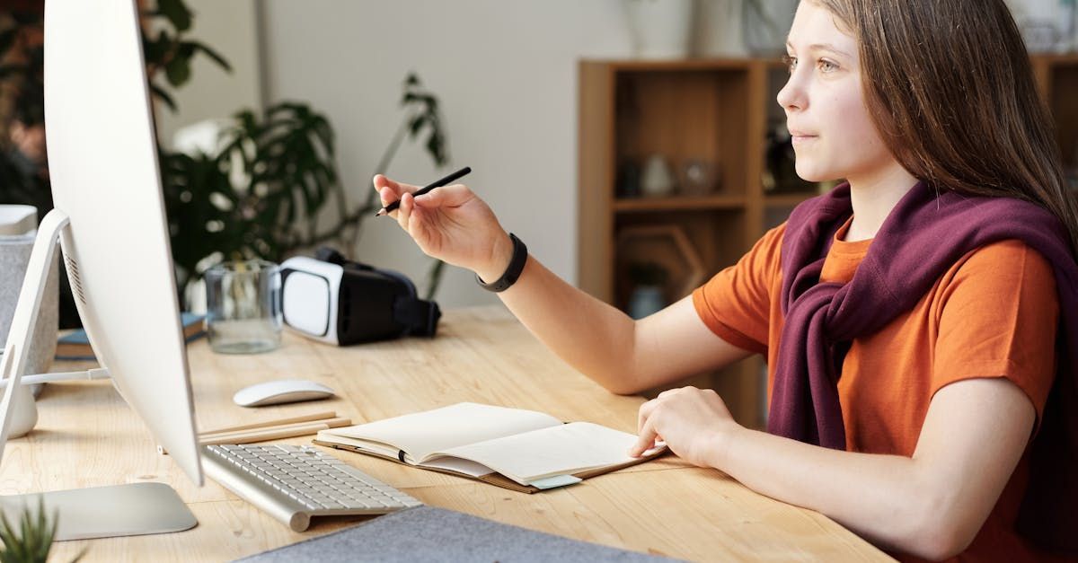 A young woman is sitting at a desk in front of a computer.