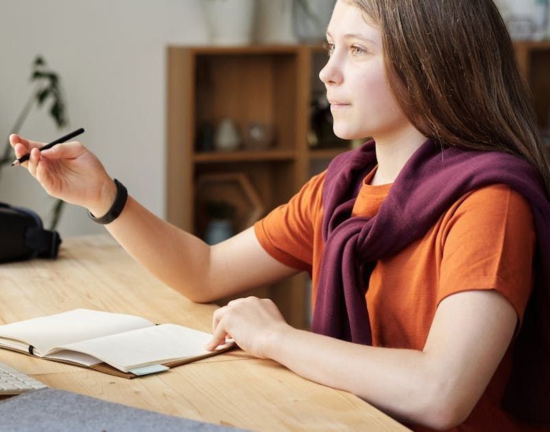 A young woman is sitting at a desk in front of a computer.