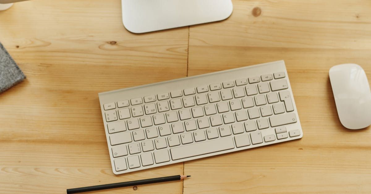 A keyboard , mouse , and pencil are on a wooden desk.
