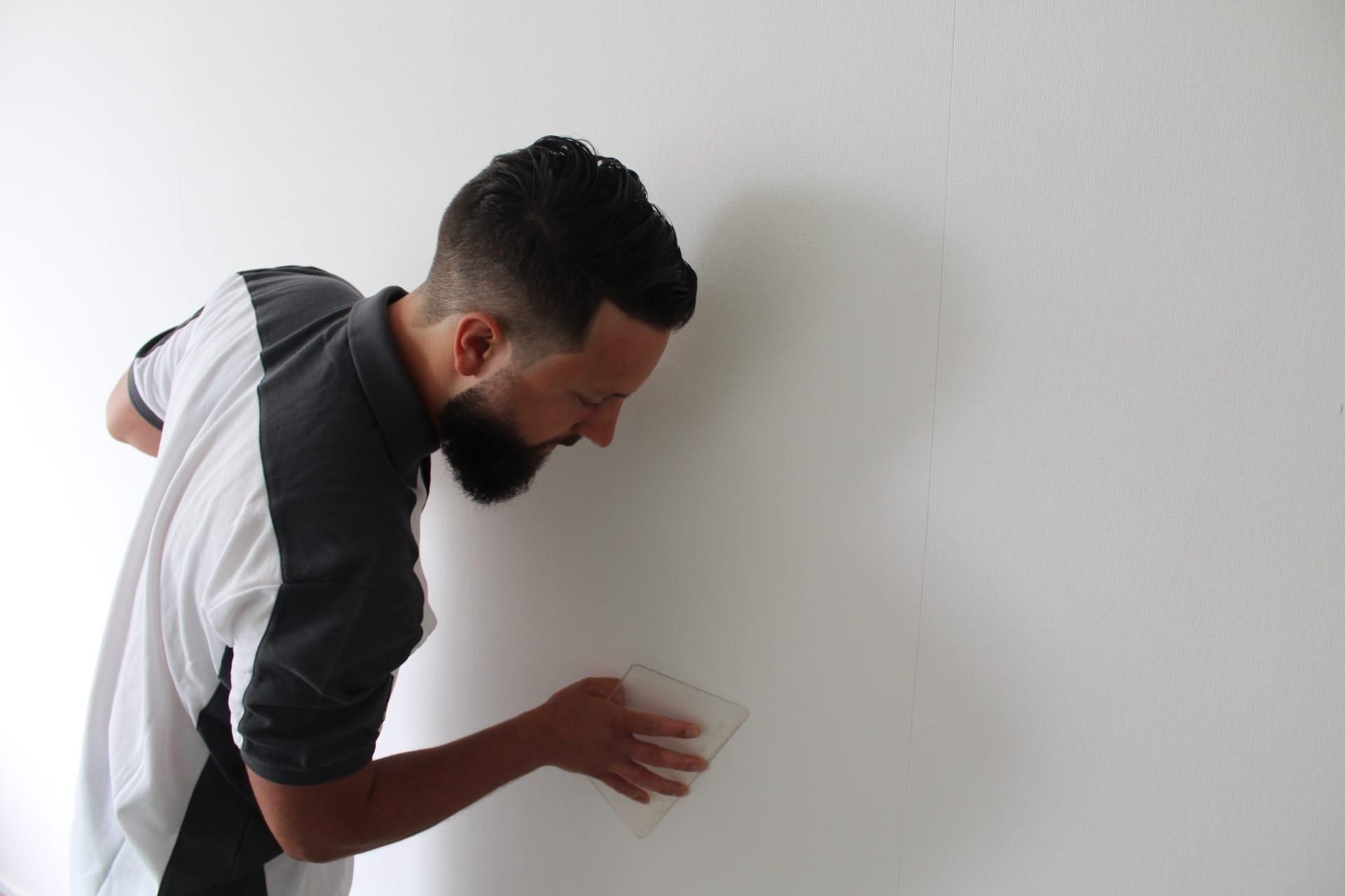 Professionele behanger is de net behangde muur aan het afwerken