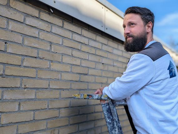 Schilder in Lichtenvoorde die bezig is met het schilderen van een gevel van een woning