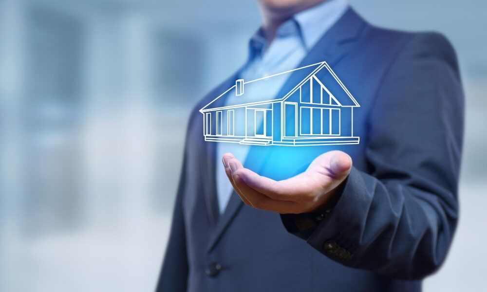 A Man in A Suit Is Holding a Drawing of A House — Outback Conveyancing Services in Alice Springs, NT