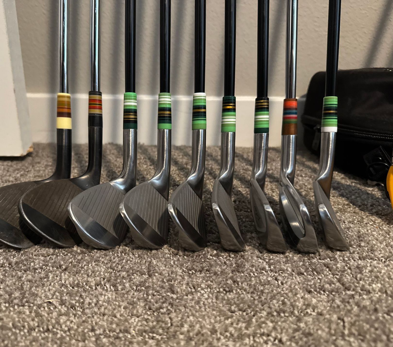 A bunch of golf clubs are lined up on the floor