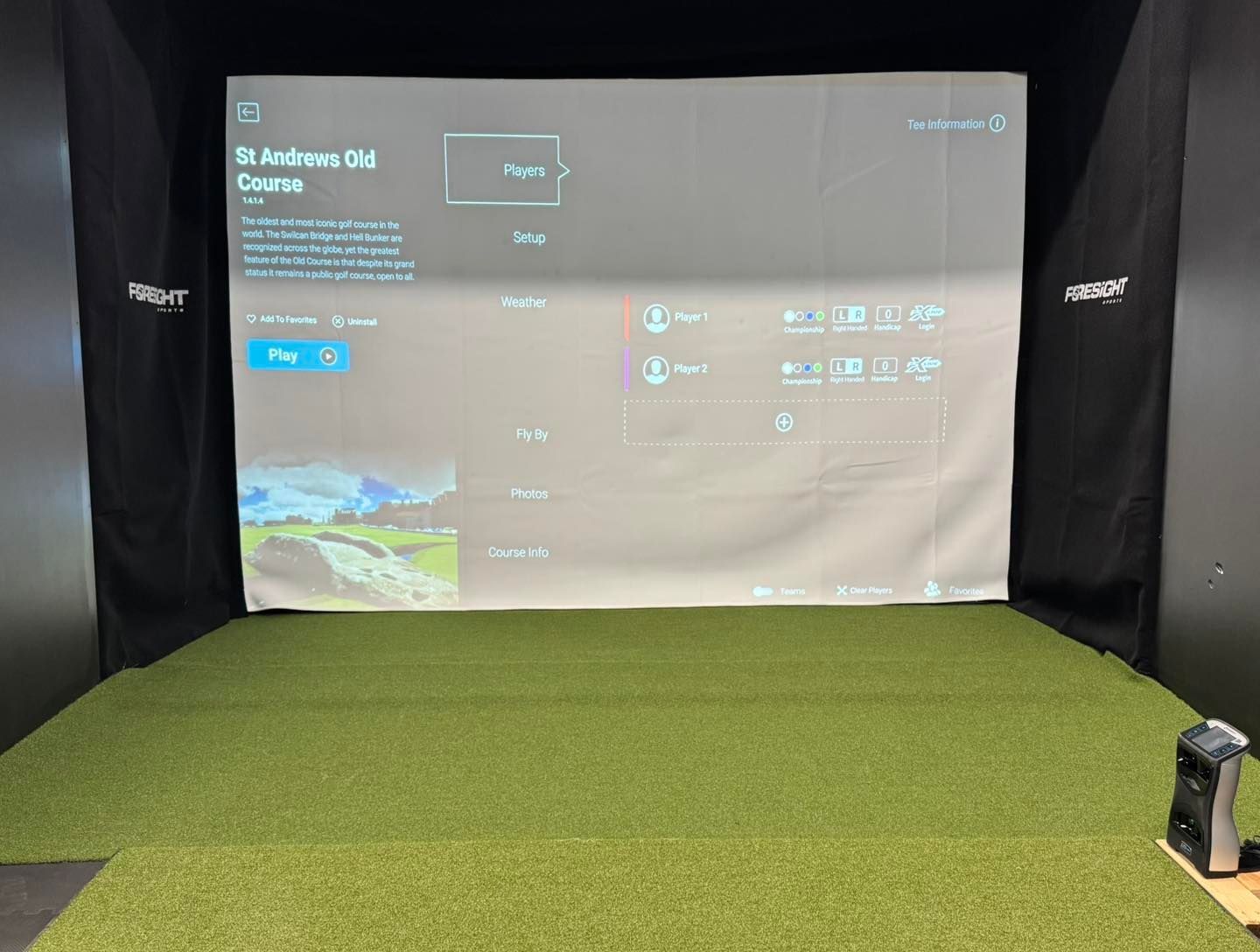 A golf simulator with a large screen on the wall.