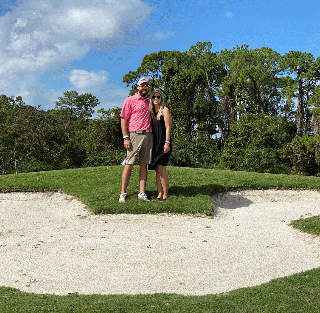 A man and a woman are posing for a picture on a golf course