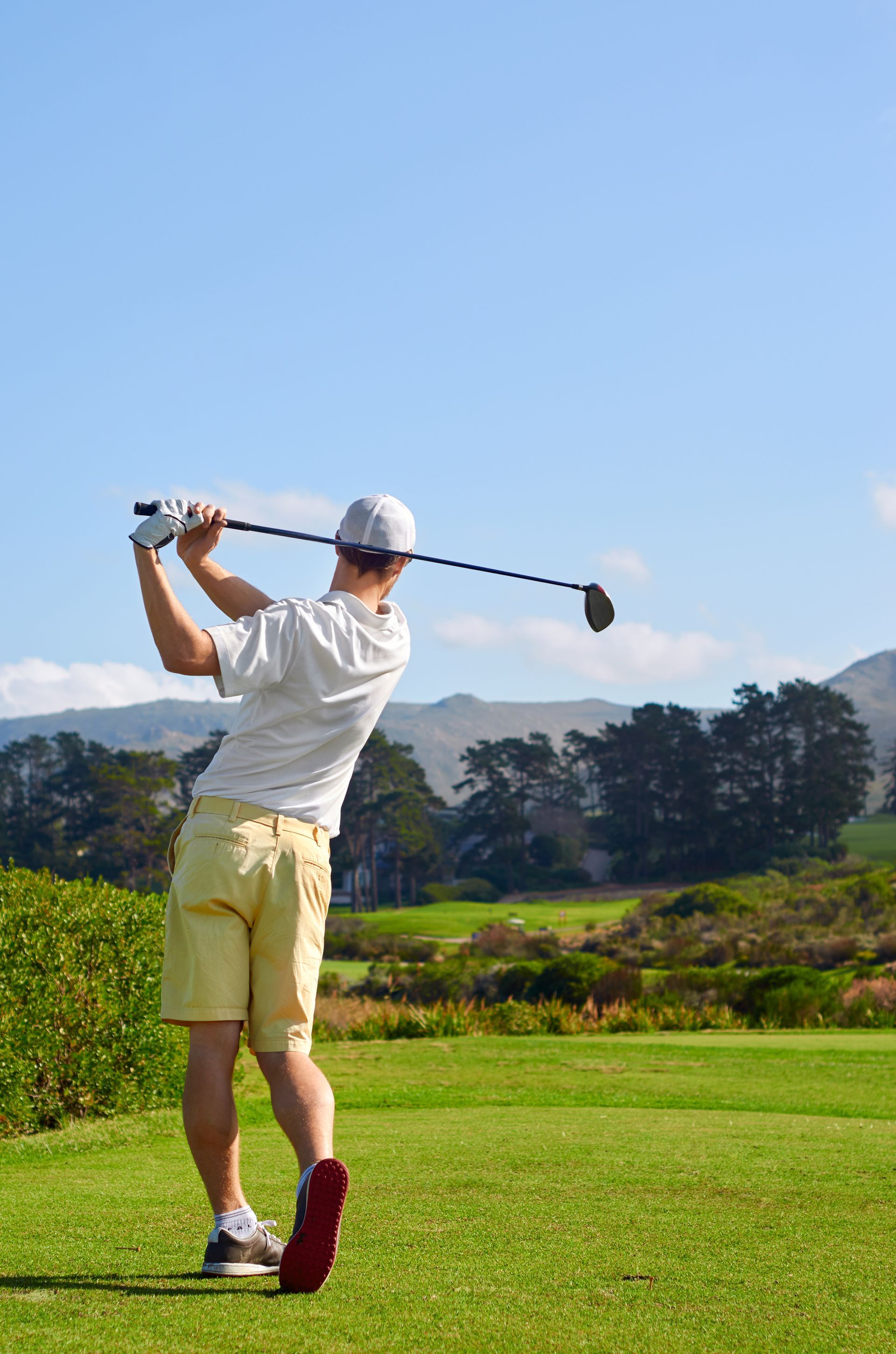 A man is swinging a golf club on a golf course.
