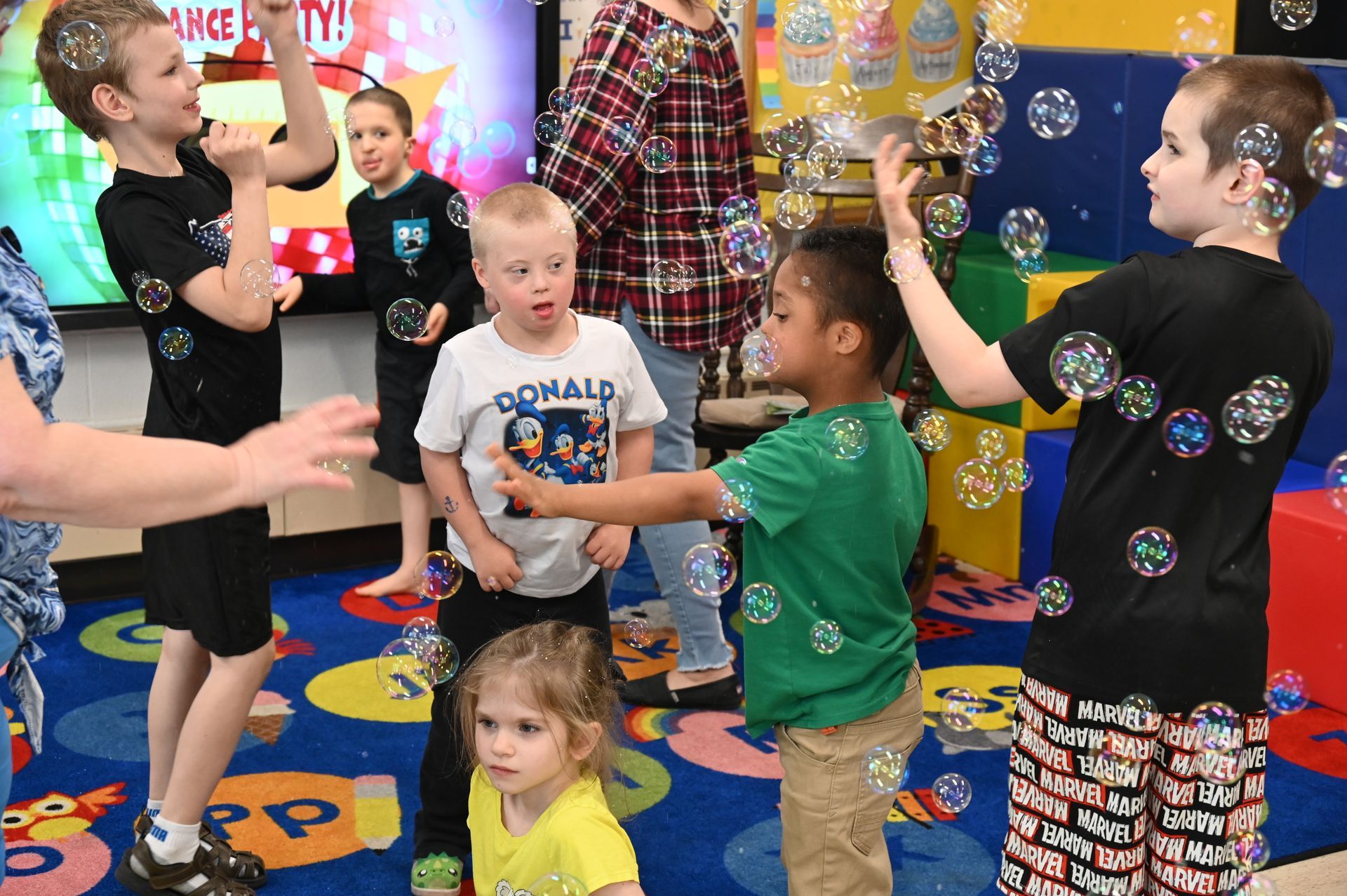 Children playing with bubbles in a classroom.