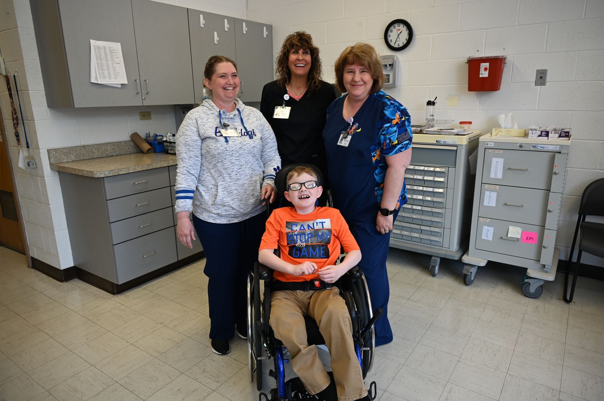 Boy in wheelchair with three medical professionals in a clinic setting.
