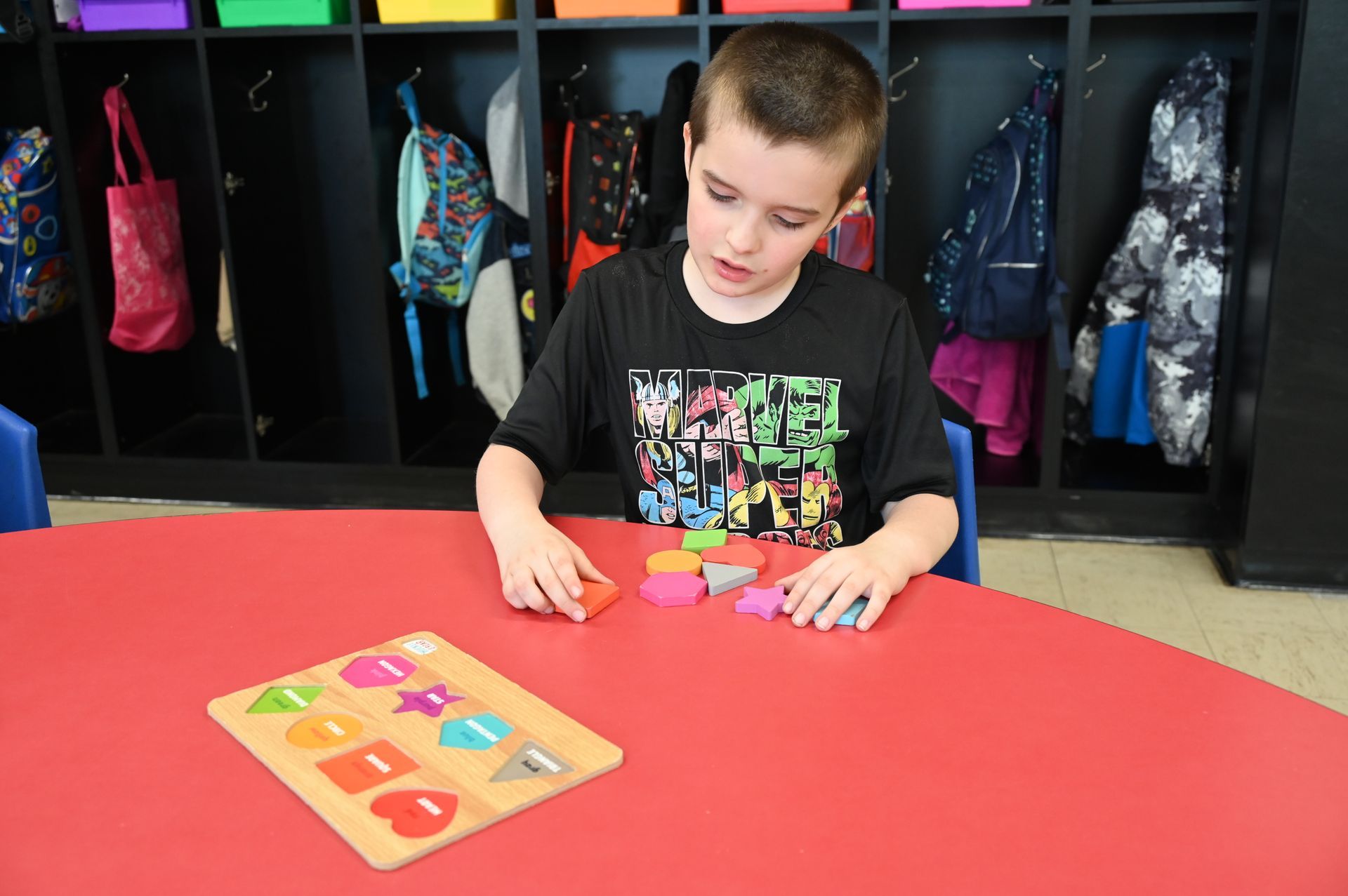 A child is sitting at a table and plays with a puzzle.