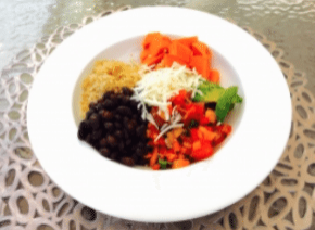 White bowl with black beans, quinoa, carrot, salsa, avocado, and shredded cheese.