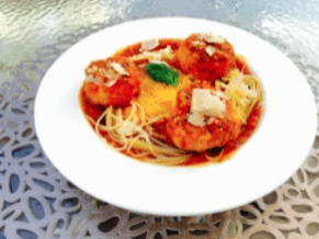 Plate of spaghetti with meatballs in tomato sauce, sprinkled with cheese.