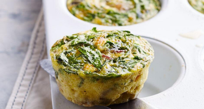 Spinach and egg muffins in a white muffin tin.