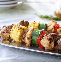 Chicken and vegetable skewers on a metal platter. Grilled chicken, corn, peppers and mushrooms.