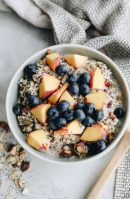 Bowl of oatmeal topped with blueberries and peach slices.
