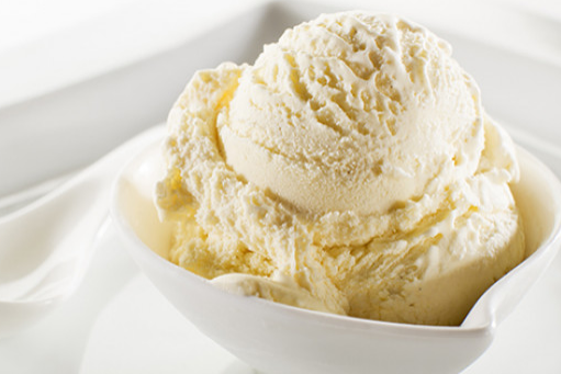 Vanilla ice cream scoops in a white bowl, close-up.
