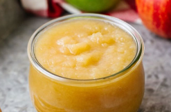 A small glass jar filled with chunky, light-brown applesauce.