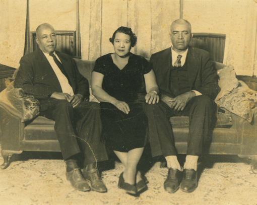 Three adults sit on a couch in a vintage sepia-toned portrait.