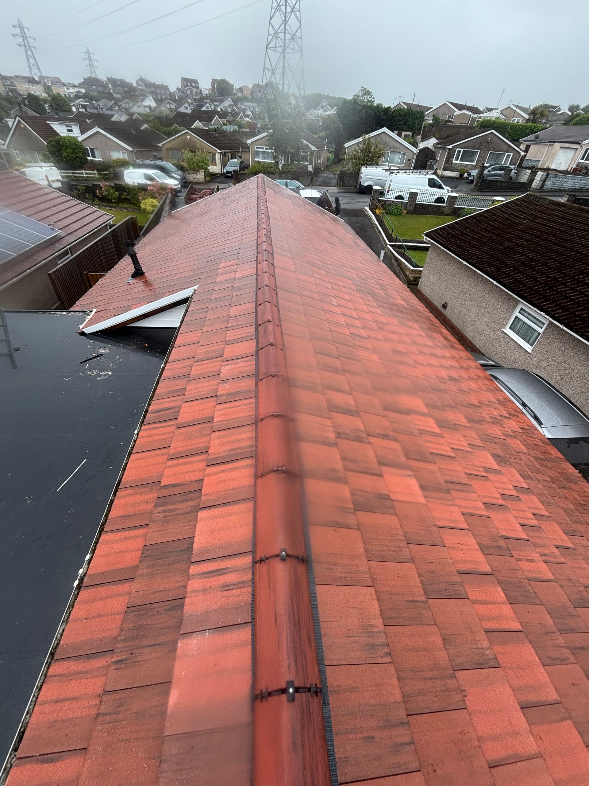 View from a wet red-tiled roof over suburban houses on a rainy day
