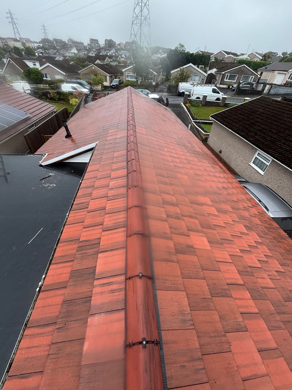 View from a wet red-tiled roof over suburban houses on a rainy day