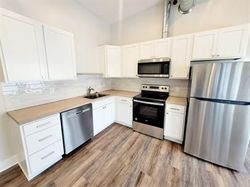 Bright white kitchen with stainless steel appliances, wood countertops, and wood-look flooring