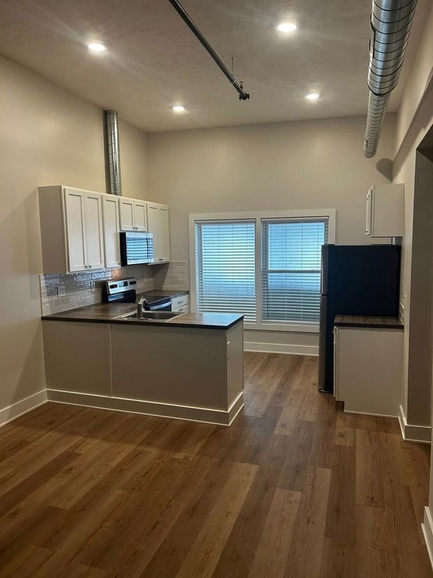 Modern kitchen with white cabinets, wood floors, island, and a windowed door at the back