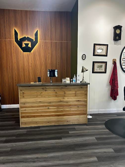 Wood-paneled reception desk in a modern office lobby with dark flooring and wall decor.