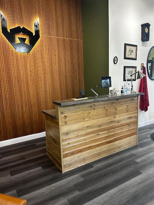 Reception desk in a modern office with wood walls, dark flooring, and wall decor.