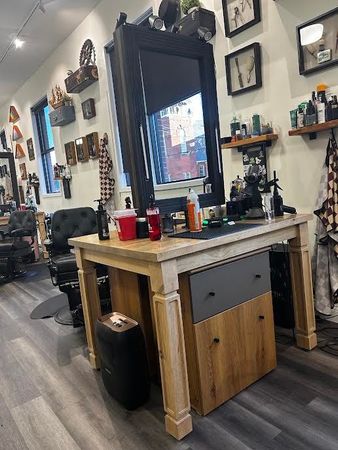 Barbershop interior with a mirror station, chairs, wall shelves, and grooming tools on a wooden counter