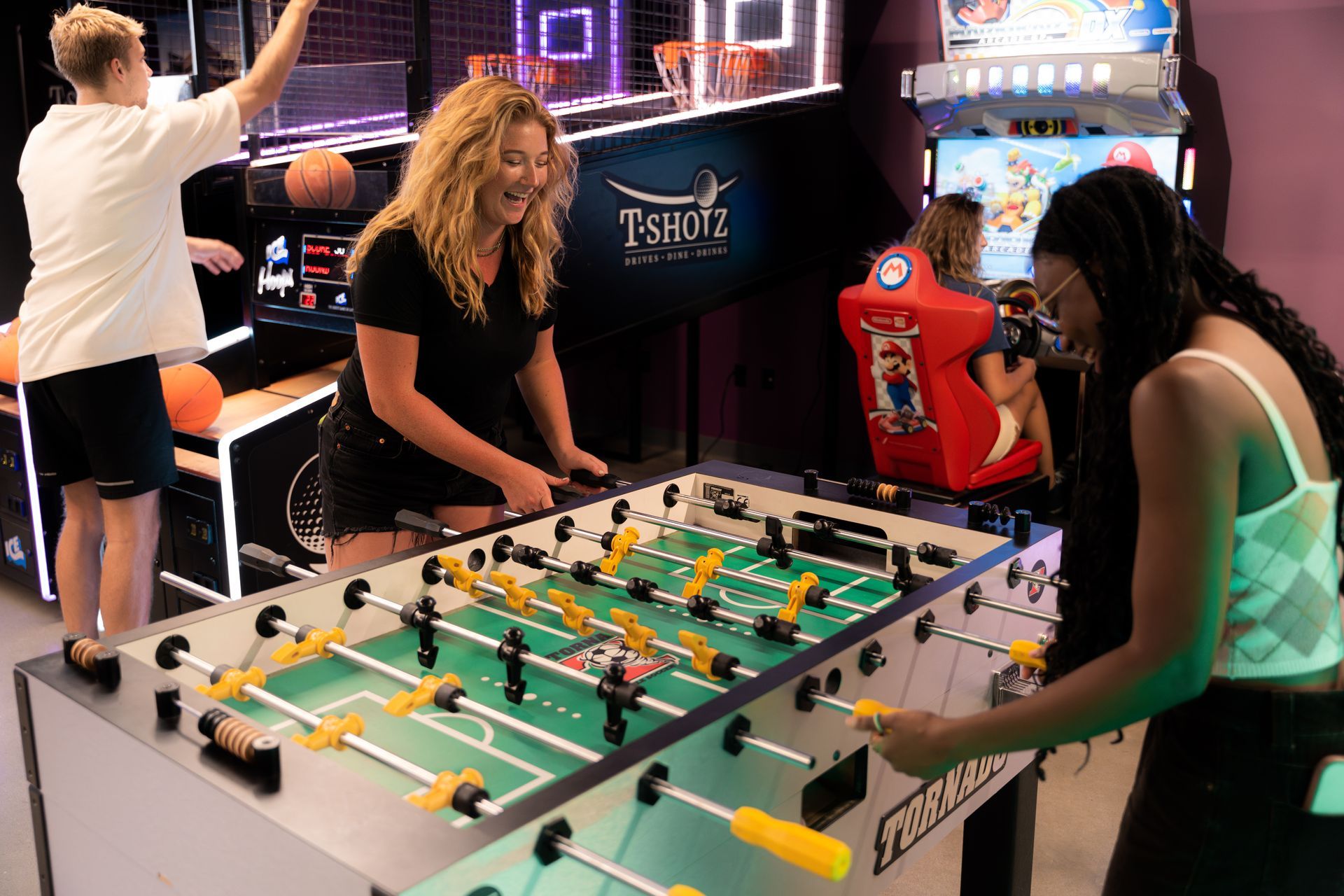 A group of people are playing foosball in an arcade.
