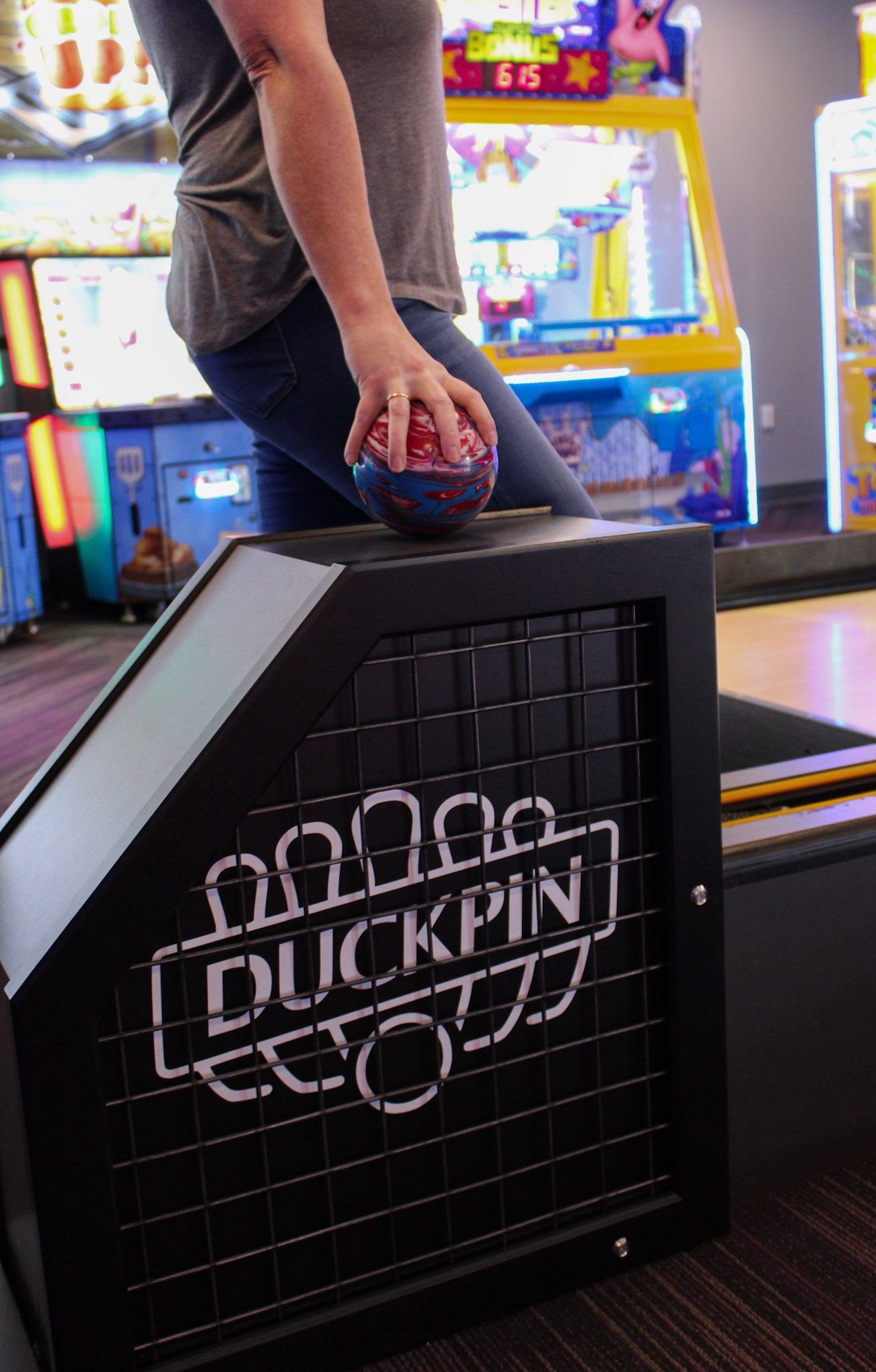 Person holding a duckpin bowling ball over a Duckpin game.
