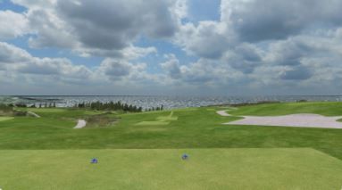 A golf course with a view of the ocean on a cloudy day.