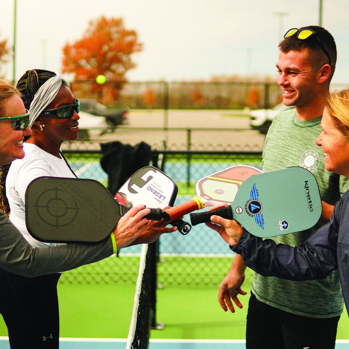A group of people holding paddle rackets on a tennis court