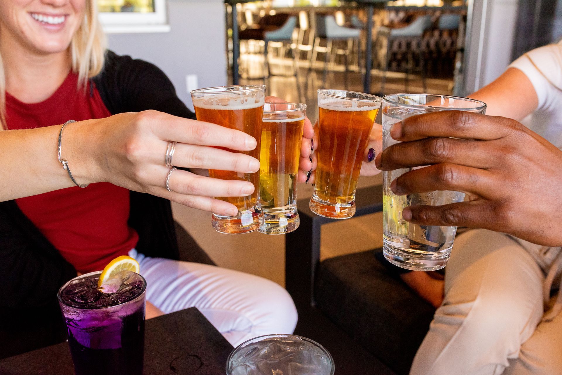 A group of people are sitting at a table toasting with beer glasses.