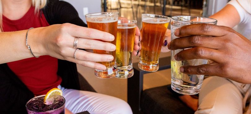 A group of people are toasting with beer and shot glasses.