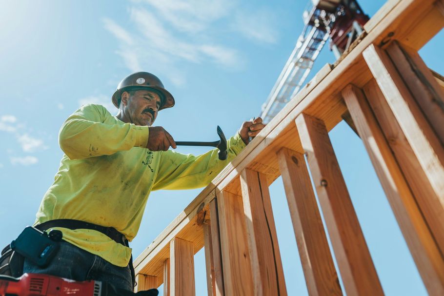 Construction worker hammering wooden framing at a building site