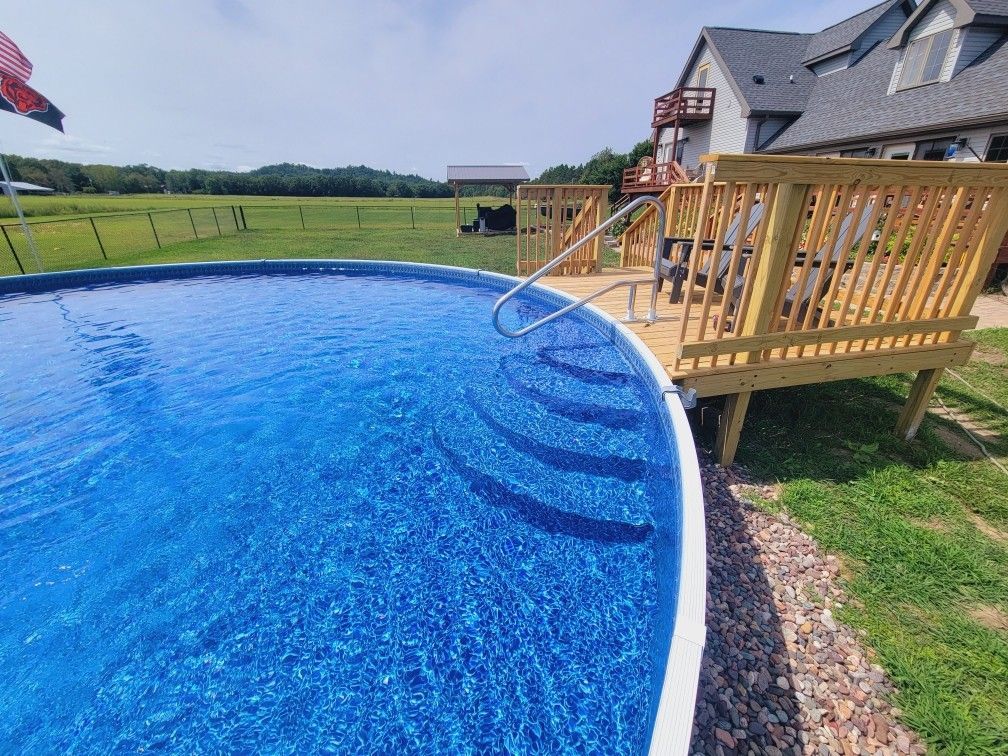 A swimming pool with stairs leading to it and a wooden deck. A swimming pool with stairs leading to it and a wooden deck.