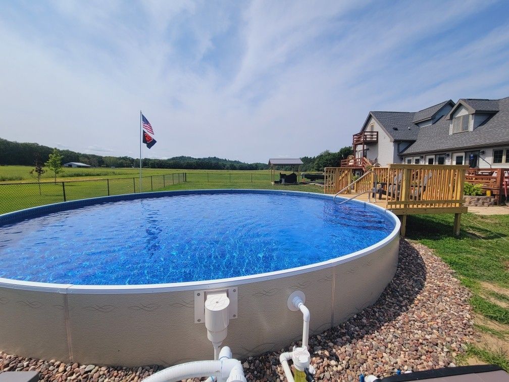A large swimming pool is in the backyard of a house.