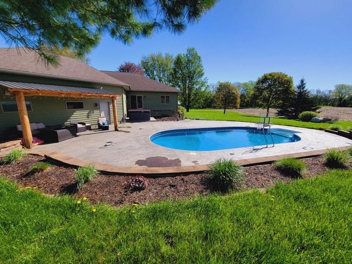A large blue swimming pool is being built in a backyard. A large blue swimming pool is being built in a backyard.