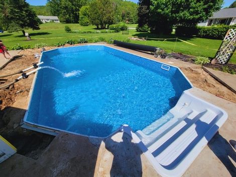A large blue swimming pool is being built in a backyard. A large blue swimming pool is being built in a backyard.