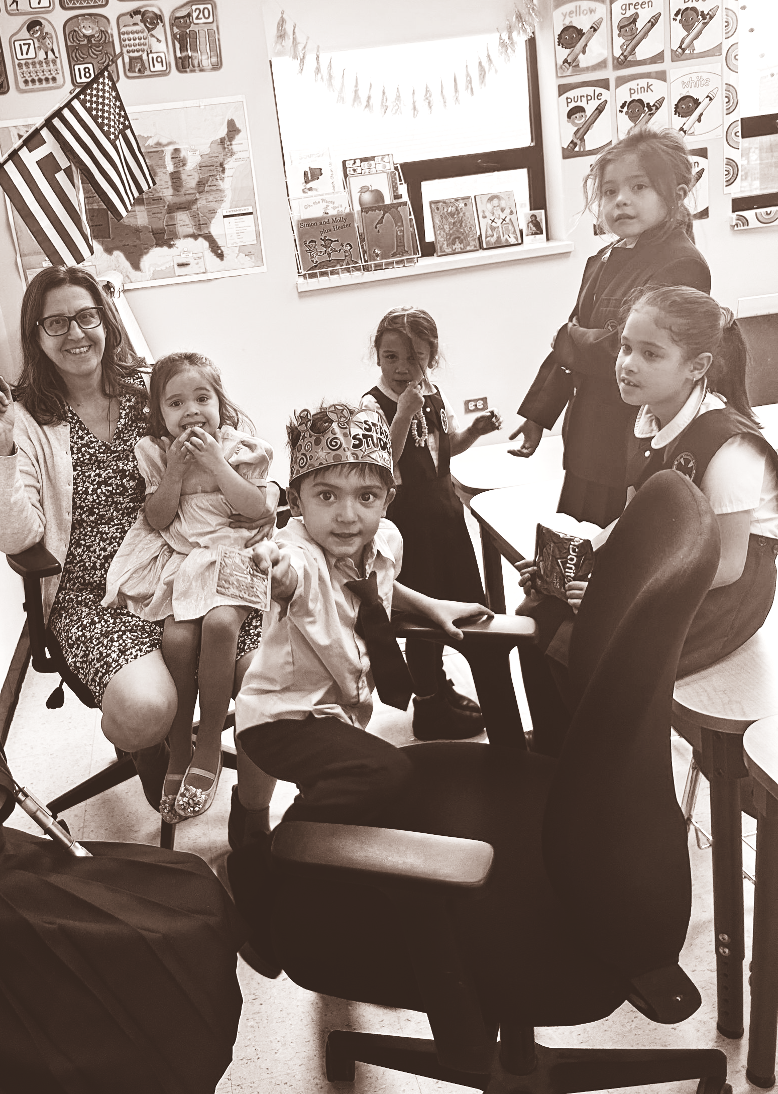 Group of people gathered indoors, smiling and posing around a table in a decorated room.