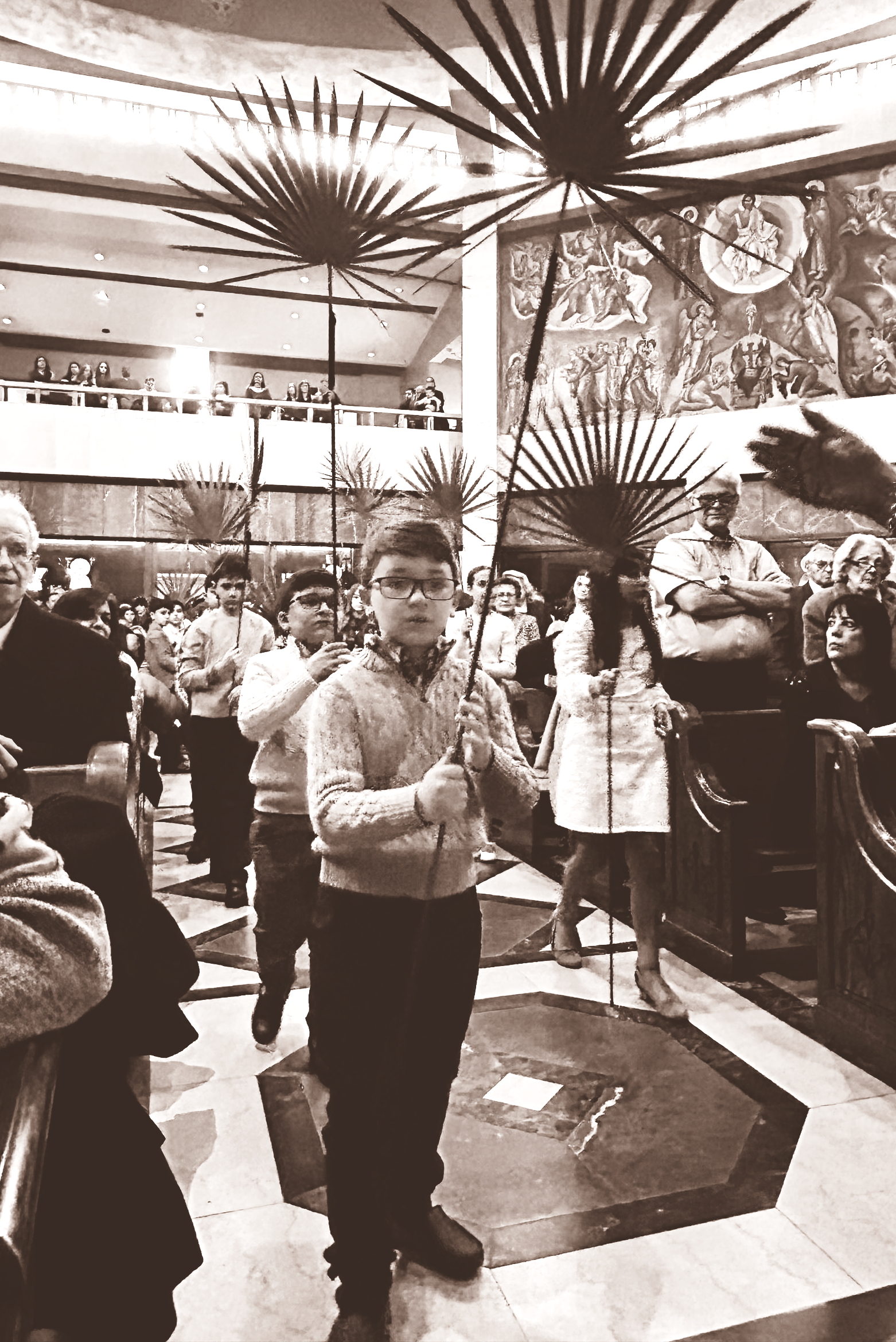 People standing in a busy indoor hallway with decorative ceiling lights and a wall clock