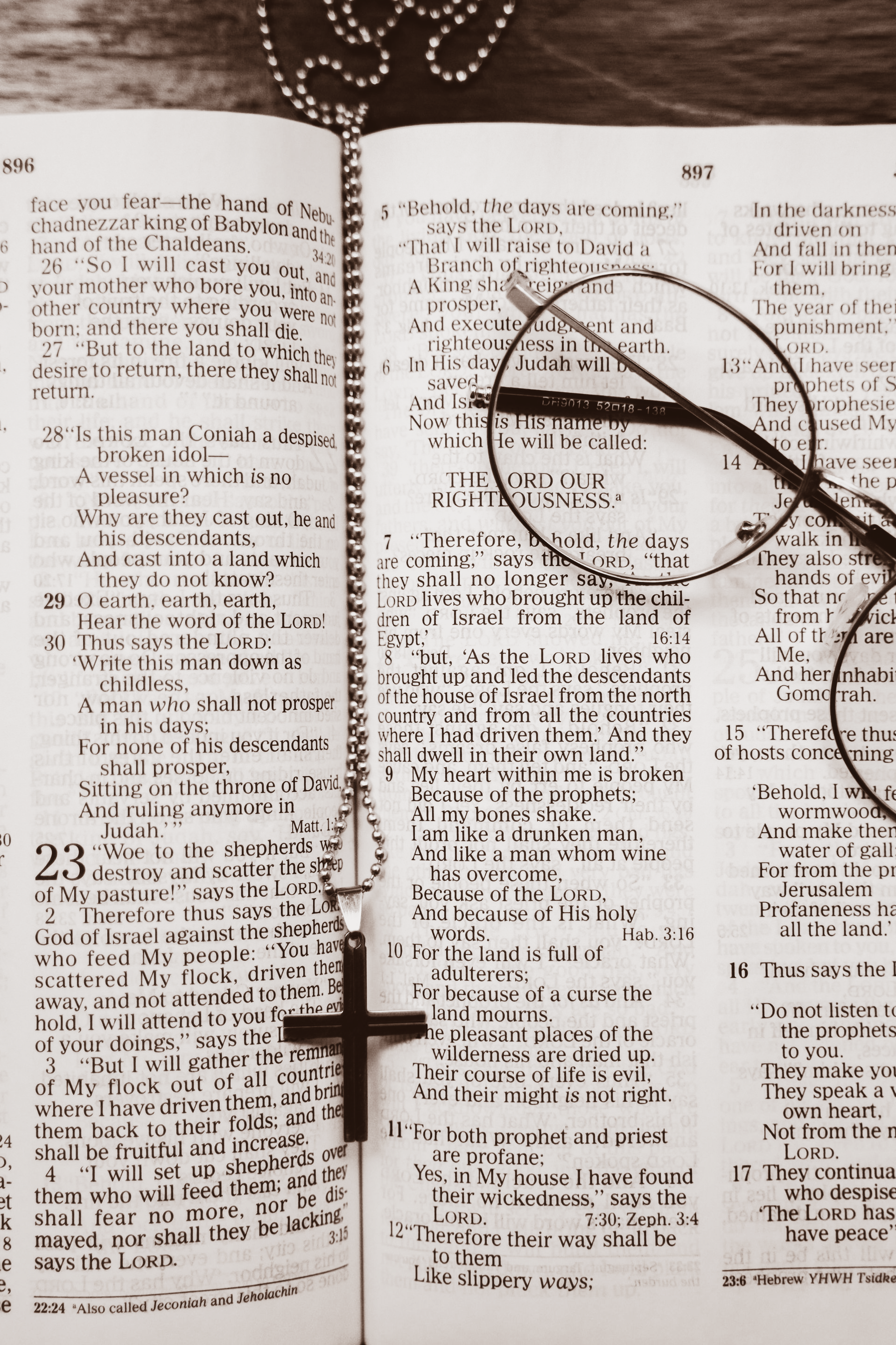 Open Bible with rosary and wooden cross resting across the pages.