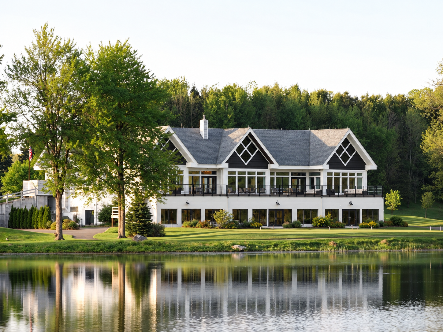 A large house sits on the shore of a lake surrounded by trees.