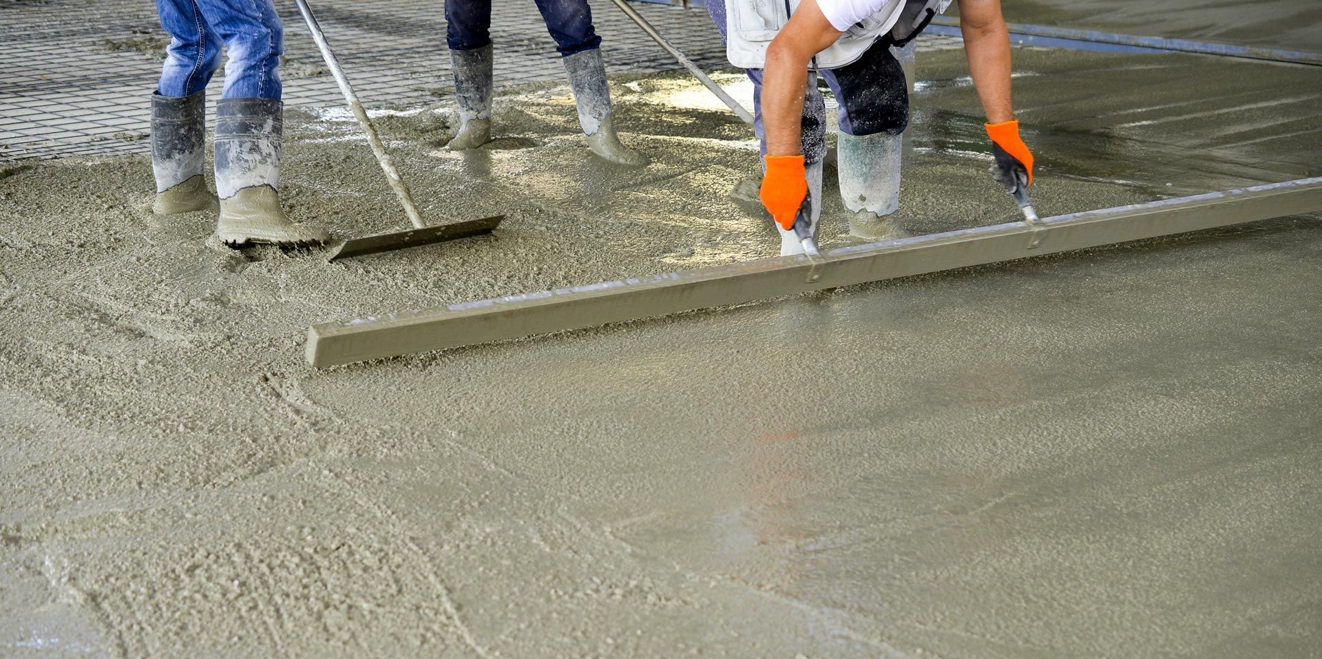 Close-up of workers leveling concrete of a new building. Close-up of workers leveling concrete of a new building.