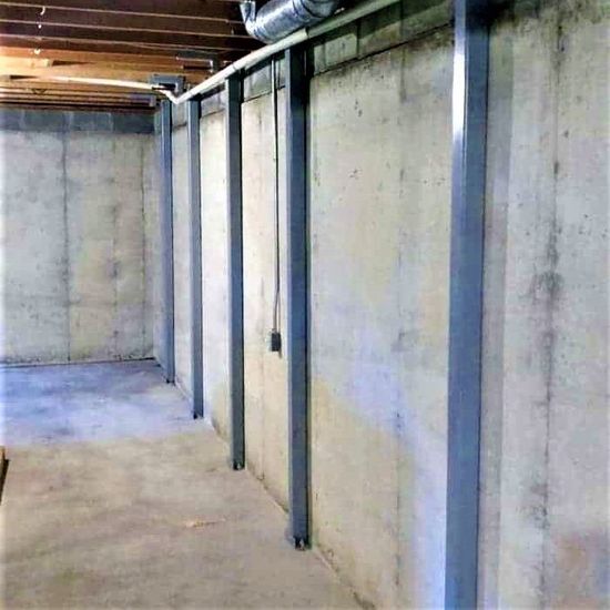 A basement with concrete walls and metal beams | Jack-A-Slab Construction